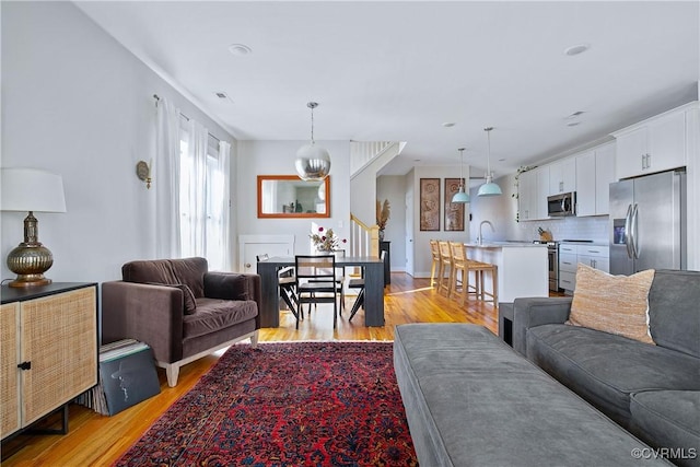 living room featuring an inviting chandelier, sink, and light hardwood / wood-style floors