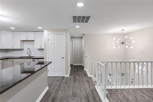 kitchen featuring white cabinetry, sink, dark hardwood / wood-style floors, and dark stone counters