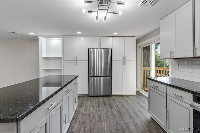 kitchen with stainless steel refrigerator, dark stone counters, tasteful backsplash, and white cabinets