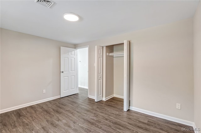 unfurnished bedroom with dark wood-type flooring and a closet