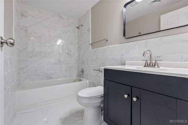 full bathroom featuring tiled shower / bath, vanity, toilet, and tile walls