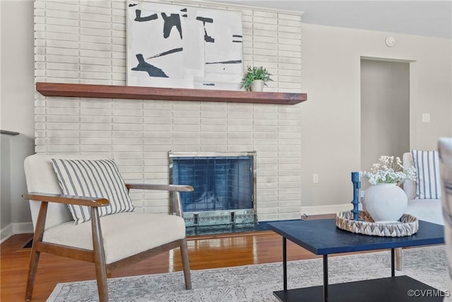 living area featuring a brick fireplace and light wood-type flooring