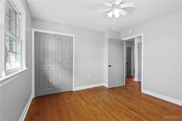 unfurnished bedroom with ceiling fan, wood-type flooring, and a closet