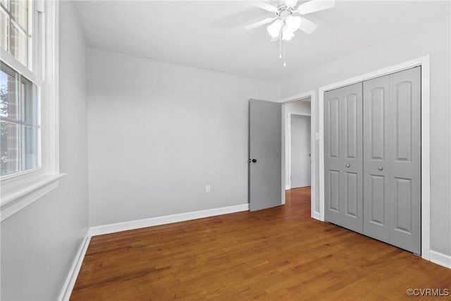 unfurnished bedroom with ceiling fan, wood-type flooring, and a closet