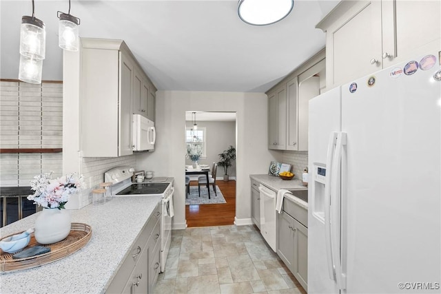 kitchen with tasteful backsplash, hanging light fixtures, white appliances, and gray cabinets