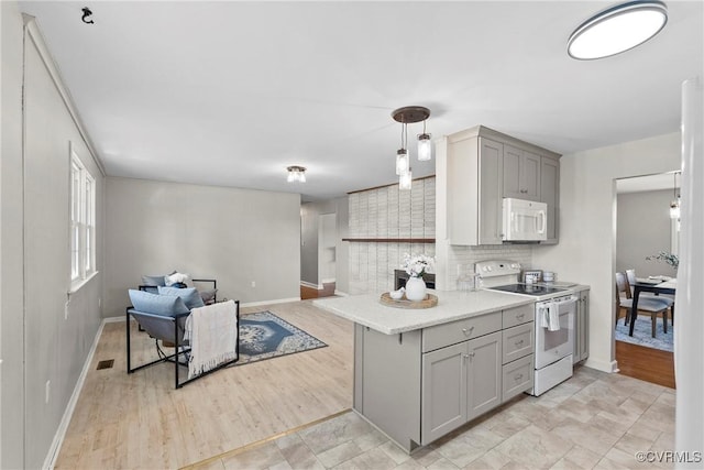 kitchen with gray cabinets, pendant lighting, backsplash, light hardwood / wood-style floors, and white appliances