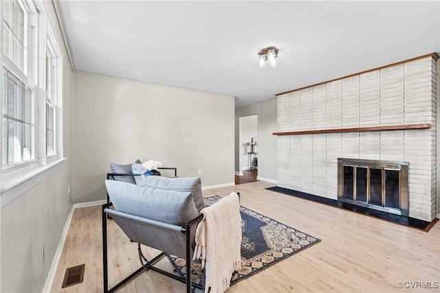 living room with a brick fireplace and wood-type flooring