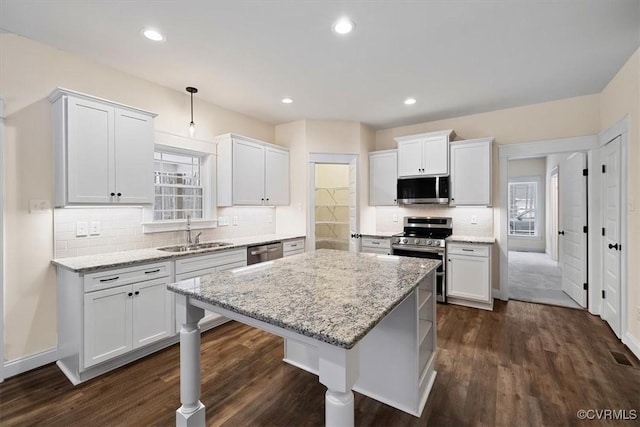 kitchen featuring white cabinetry, sink, stainless steel appliances, and a kitchen bar