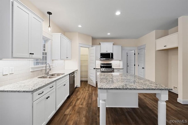 kitchen featuring stainless steel appliances, white cabinetry, hanging light fixtures, and sink