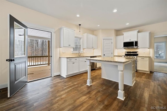 kitchen with a kitchen island, appliances with stainless steel finishes, pendant lighting, sink, and white cabinets