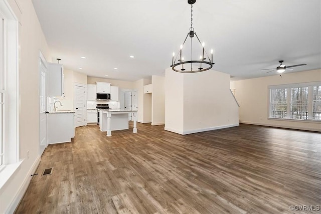 kitchen with pendant lighting, hardwood / wood-style floors, white cabinets, a kitchen island, and ceiling fan with notable chandelier