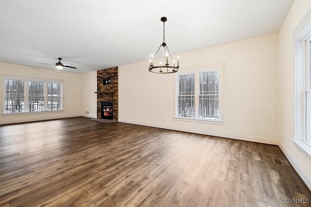 unfurnished living room featuring hardwood / wood-style flooring, a stone fireplace, and ceiling fan with notable chandelier