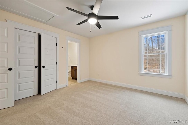 unfurnished bedroom featuring ceiling fan, ensuite bath, a closet, and light carpet