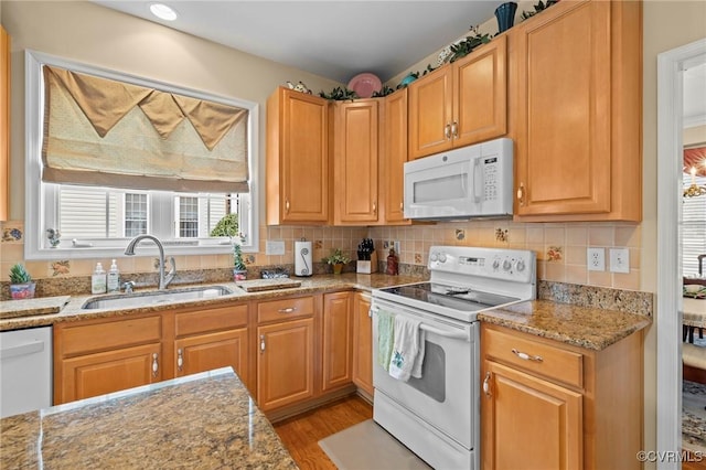 kitchen with light stone counters, white appliances, sink, and light wood-type flooring