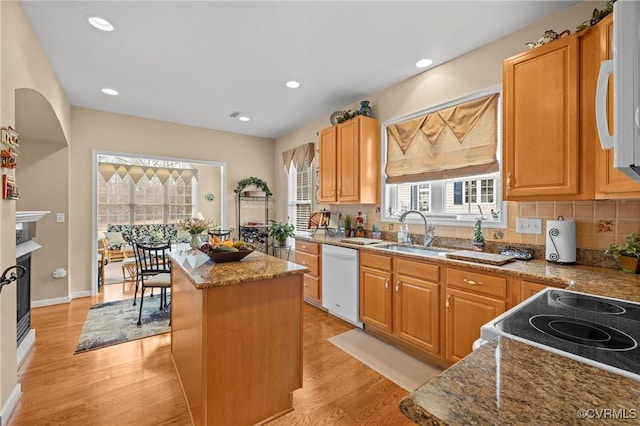 kitchen featuring sink, white appliances, a center island, light stone counters, and light hardwood / wood-style floors