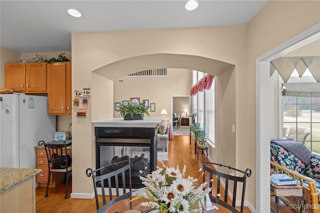 dining room featuring a multi sided fireplace and light hardwood / wood-style flooring