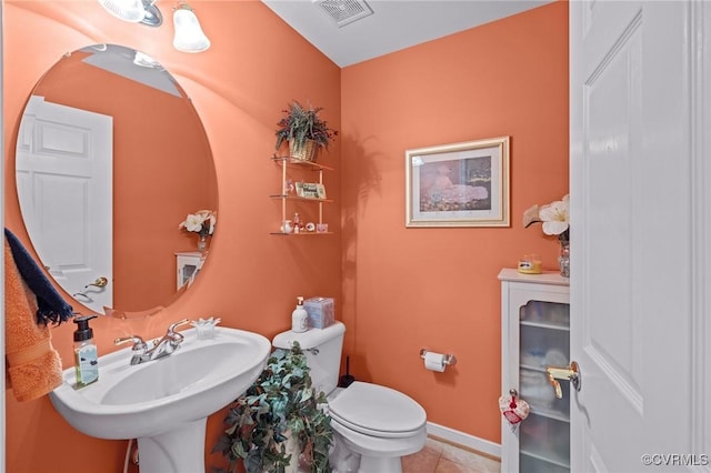 bathroom with toilet, sink, and tile patterned flooring