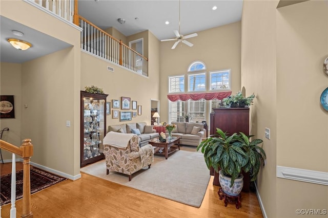 living room featuring ceiling fan, a towering ceiling, and hardwood / wood-style floors