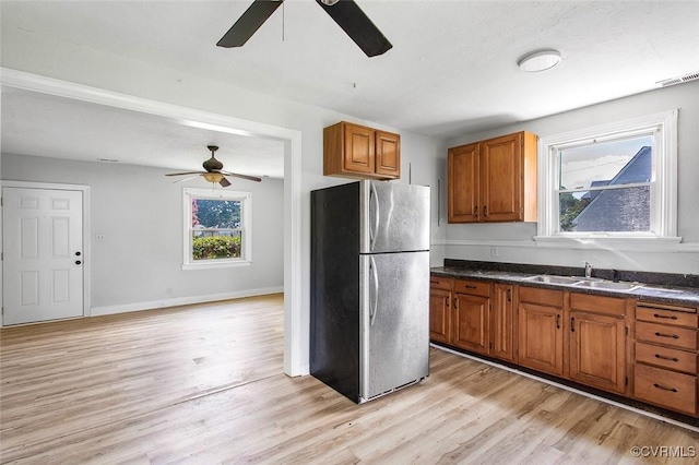 kitchen with plenty of natural light, stainless steel fridge, light hardwood / wood-style floors, and sink