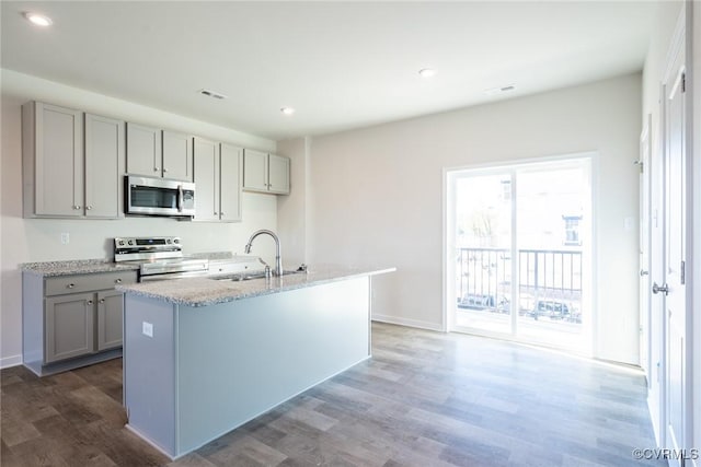 kitchen featuring gray cabinets, sink, dark hardwood / wood-style flooring, stainless steel appliances, and a center island with sink