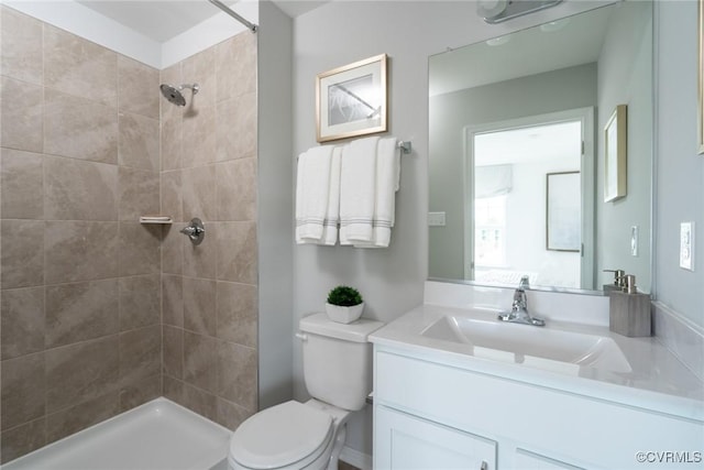 bathroom with vanity, toilet, and tiled shower