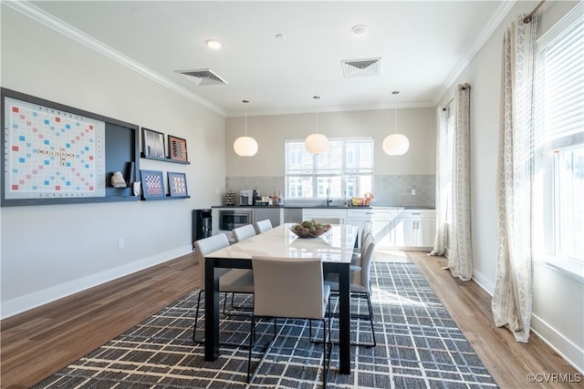 dining space with sink, dark wood-type flooring, and ornamental molding