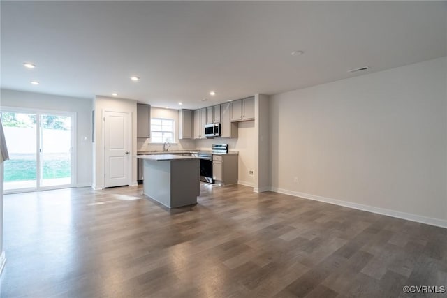 kitchen featuring sink, appliances with stainless steel finishes, gray cabinetry, a center island, and dark hardwood / wood-style flooring