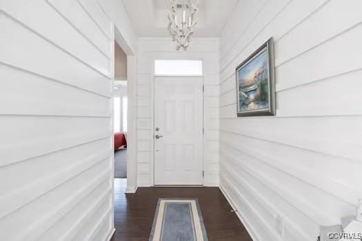 doorway to outside with dark hardwood / wood-style floors and a notable chandelier