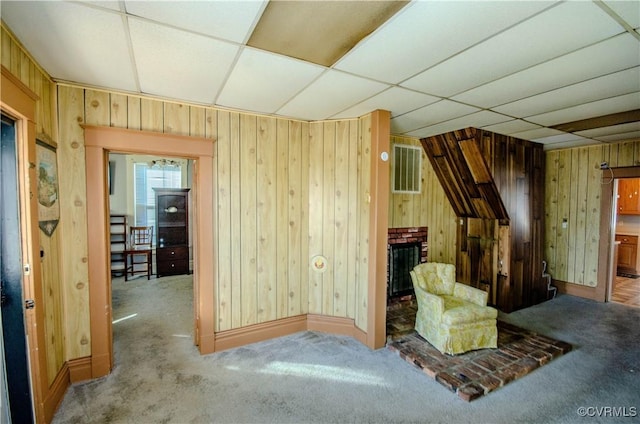 unfurnished room with a brick fireplace, carpet floors, and a drop ceiling