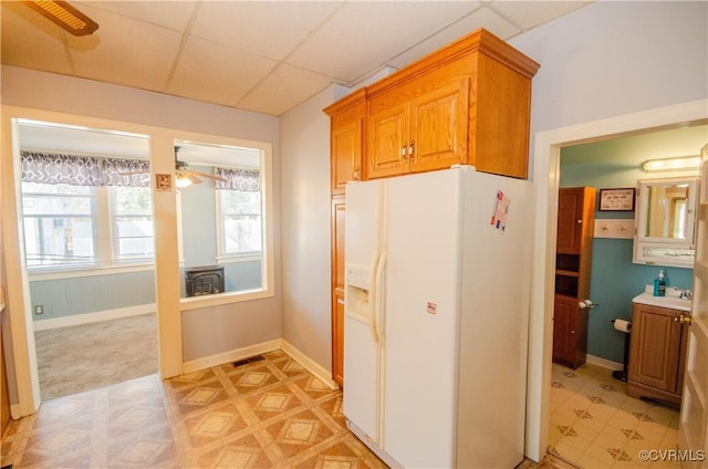 kitchen with white refrigerator with ice dispenser, ceiling fan, and a paneled ceiling