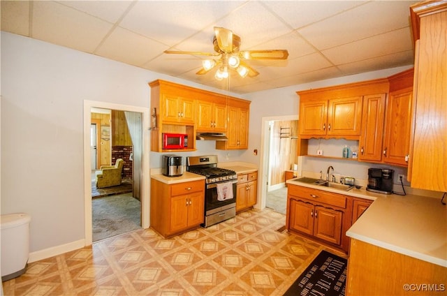 kitchen featuring stainless steel gas range oven, sink, a drop ceiling, and ceiling fan