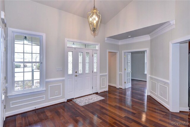 foyer with crown molding, lofted ceiling, dark wood-type flooring, and an inviting chandelier