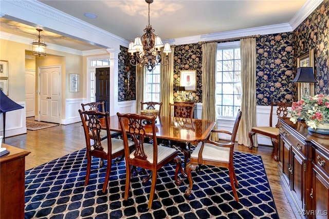 dining space featuring a wainscoted wall, wood finished floors, decorative columns, and crown molding