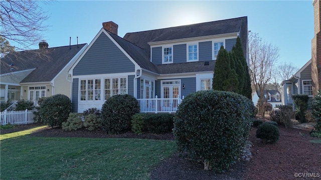 view of front of home with a front lawn, a chimney, and fence