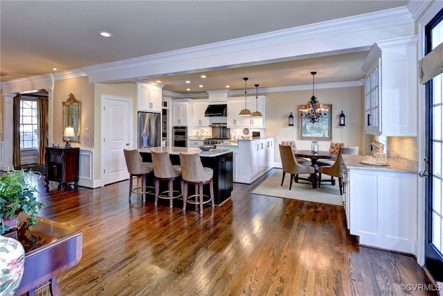 kitchen with a kitchen island, appliances with stainless steel finishes, a kitchen breakfast bar, light countertops, and white cabinetry