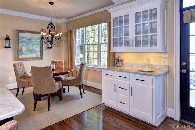 dining room featuring dark wood-style floors, a notable chandelier, ornamental molding, and baseboards