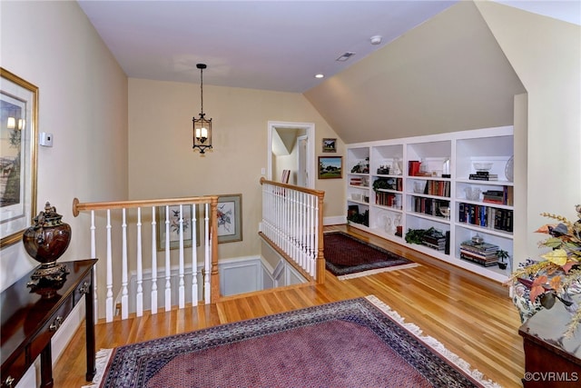 interior space featuring built in features, lofted ceiling, an upstairs landing, and wood finished floors