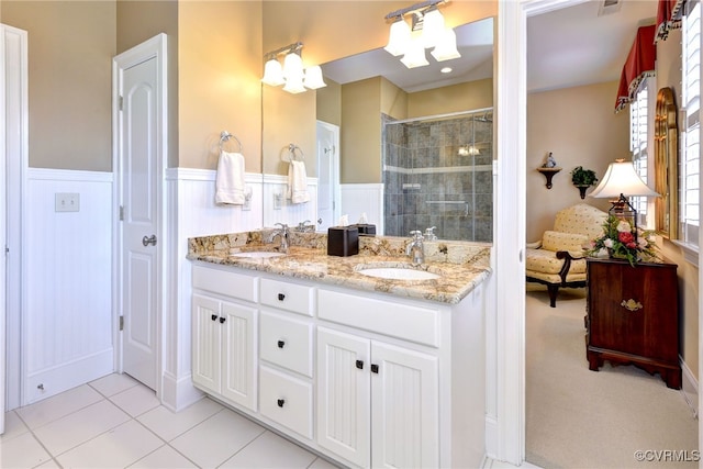 bathroom with a wainscoted wall, tiled shower, and a sink