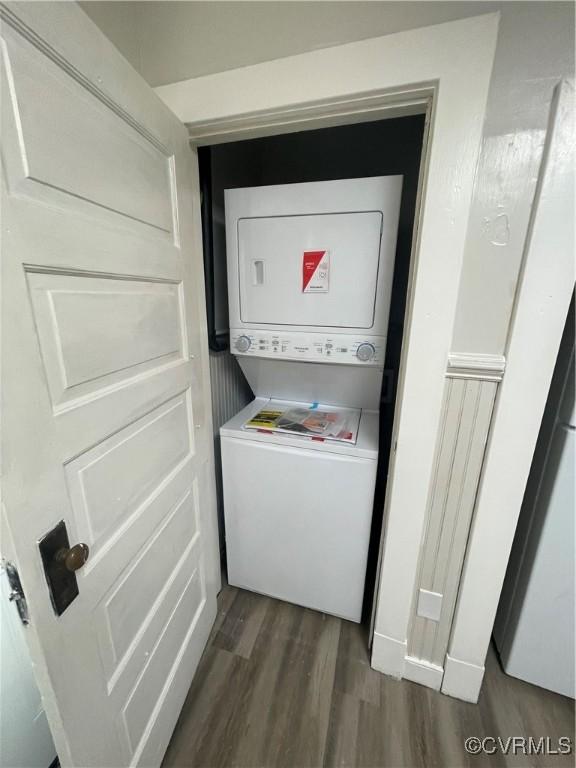 laundry area featuring stacked washer and dryer and dark hardwood / wood-style floors