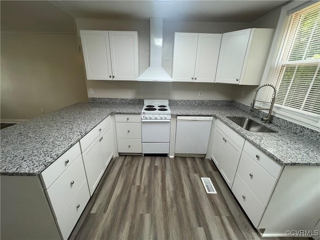 kitchen with white cabinetry, kitchen peninsula, white appliances, and wall chimney exhaust hood