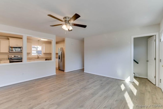 unfurnished living room with sink, ceiling fan, and light hardwood / wood-style flooring