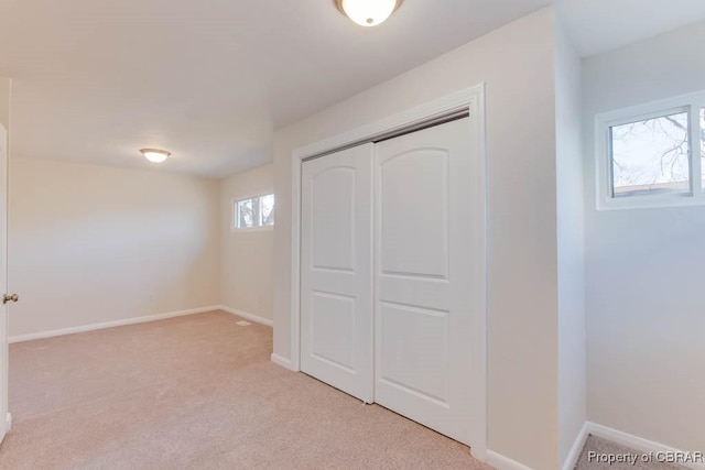 unfurnished bedroom with light colored carpet and a closet