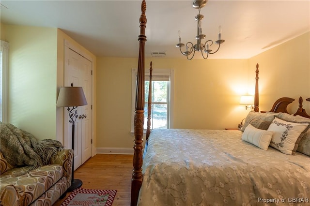 bedroom with light hardwood / wood-style flooring and a notable chandelier