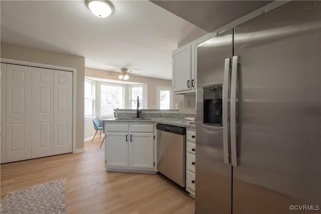 kitchen featuring white cabinetry, stainless steel appliances, light stone counters, kitchen peninsula, and light wood-type flooring