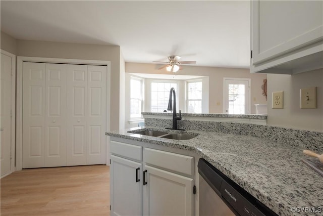 kitchen with dishwasher, sink, white cabinets, light stone counters, and light hardwood / wood-style floors