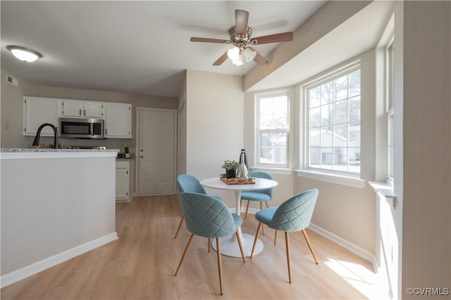 dining room with sink, light hardwood / wood-style flooring, and ceiling fan