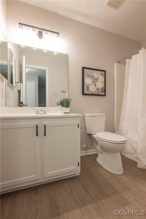 full bathroom with hardwood / wood-style flooring, vanity, shower / bath combo with shower curtain, and toilet