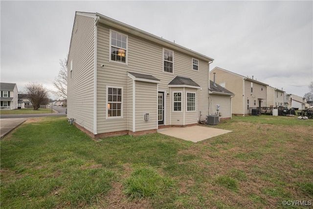 rear view of property featuring a yard, central AC unit, and a patio area