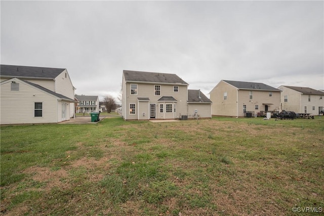 rear view of property featuring a garage and a lawn