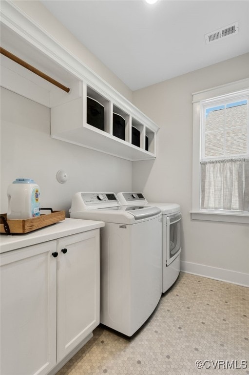 clothes washing area featuring cabinets and washing machine and clothes dryer